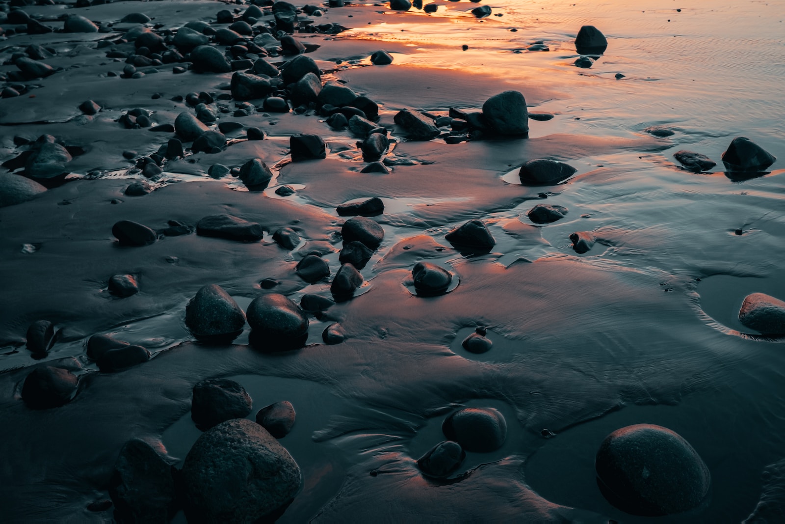 Photo by Thomas Chizzali a beach covered in lots of rocks next to the ocean