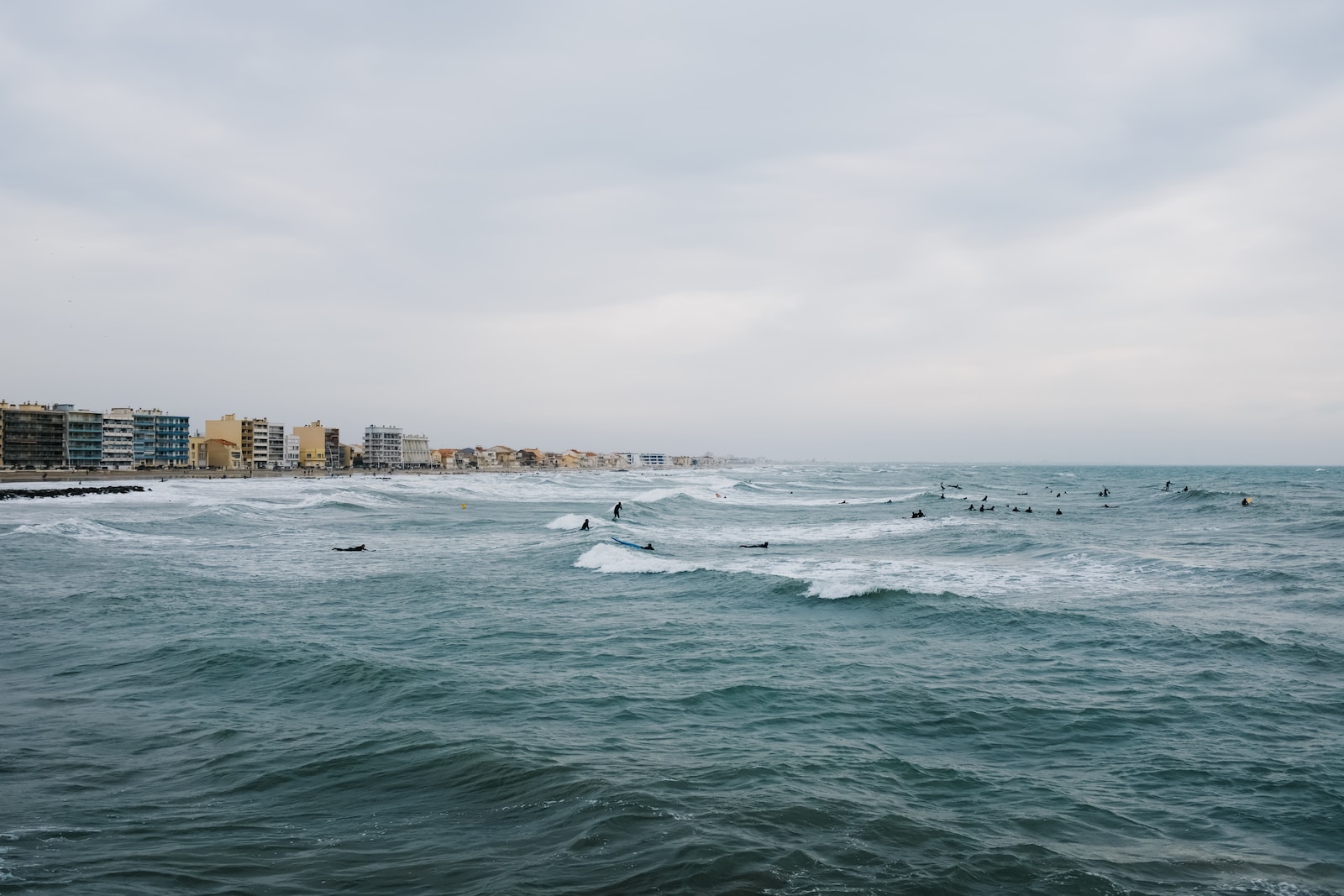 Photo by Adrien Olichon a group of people riding surfboards on top of a wave